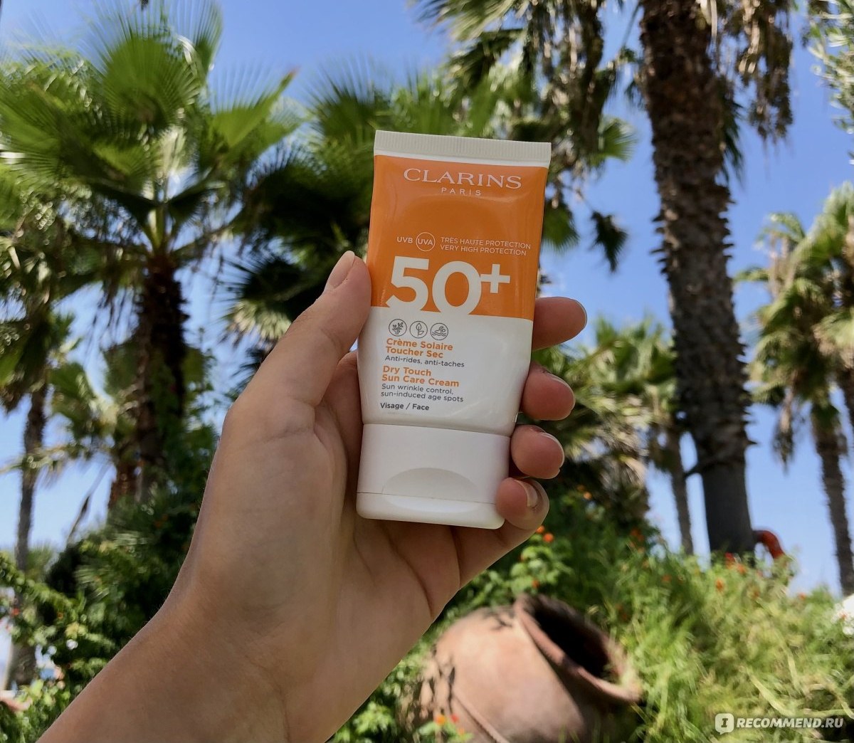 Clarins Crème Solaire Toucher Sec SPF 50+ — тюбик солнцезащитного крема для лица у пальм