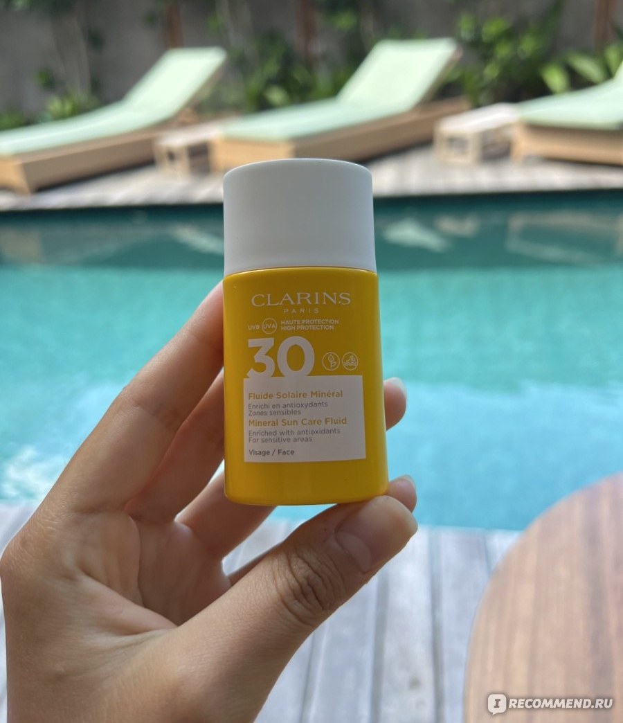 Clarins Fluide Solaire Minéral SPF 30 — жёлтый флакон минерального солнцезащитного флюида у бассейна