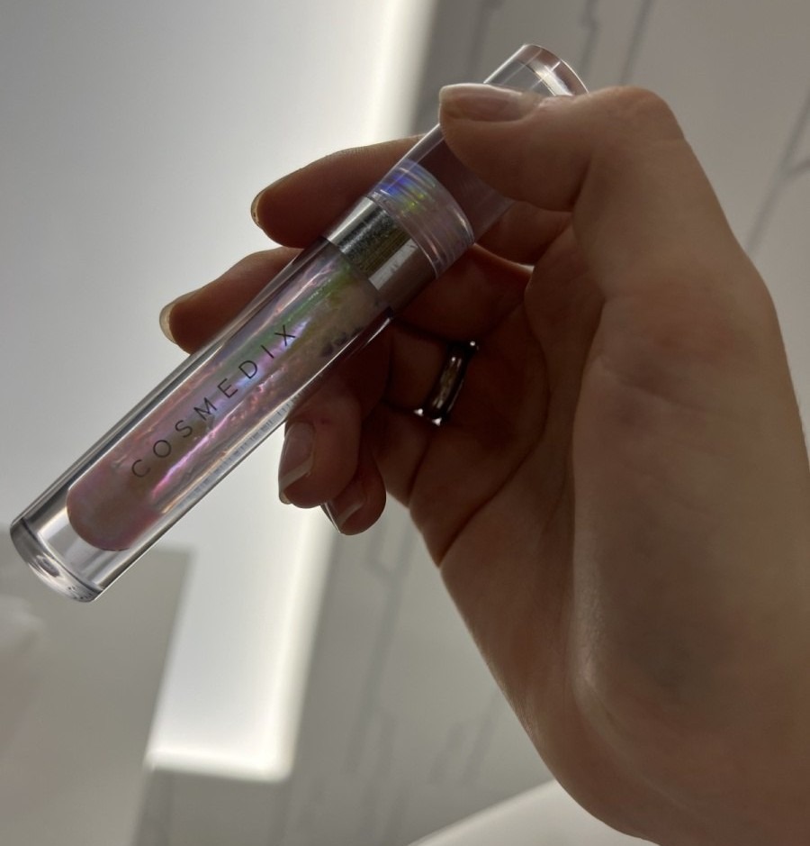 Cosmedix Lumi Crystal — голографический тюбик блеска для губ в руке