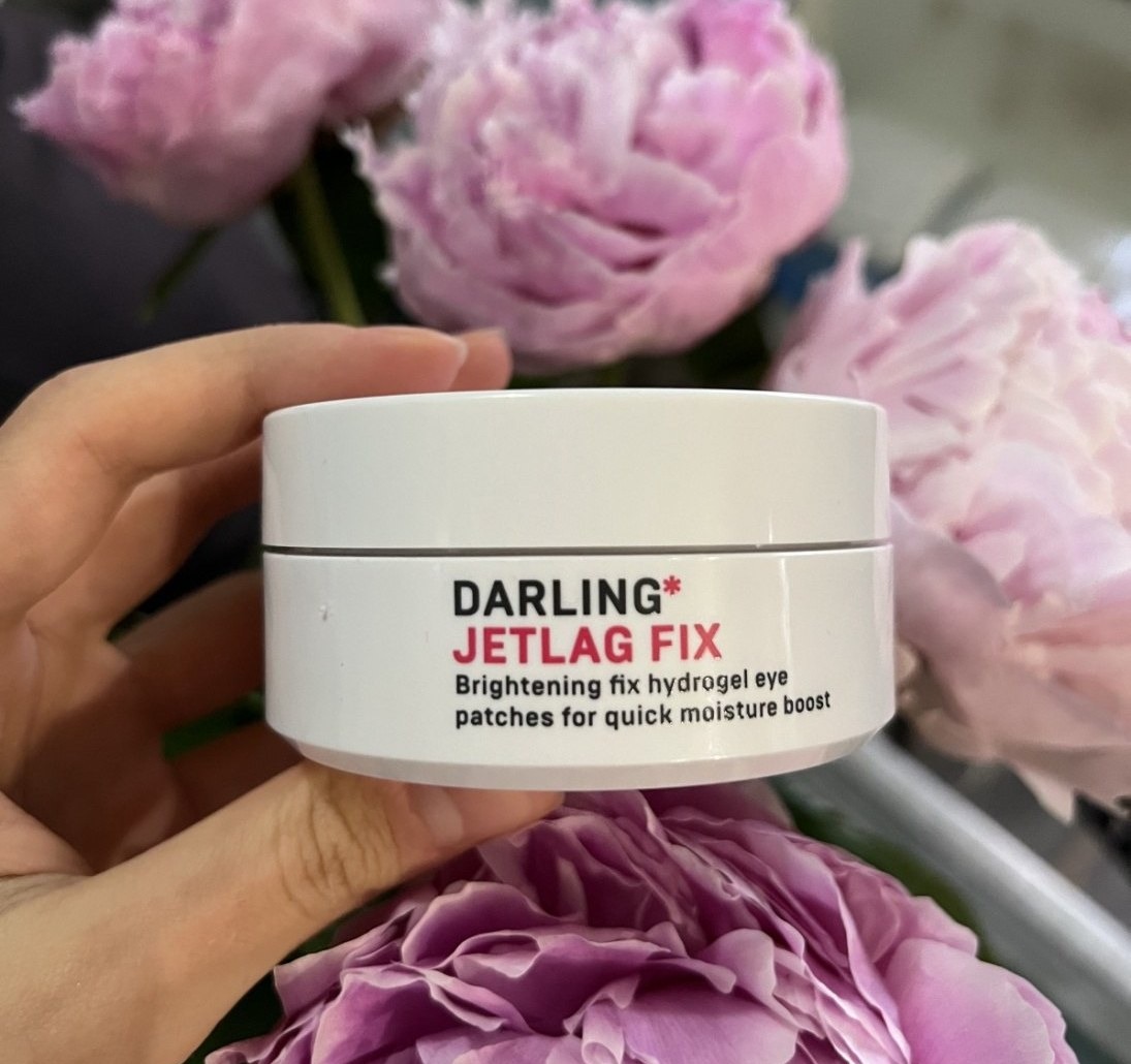 Darling Jetlag Fix — белая банка гидрогелевых патчей на фоне пионов