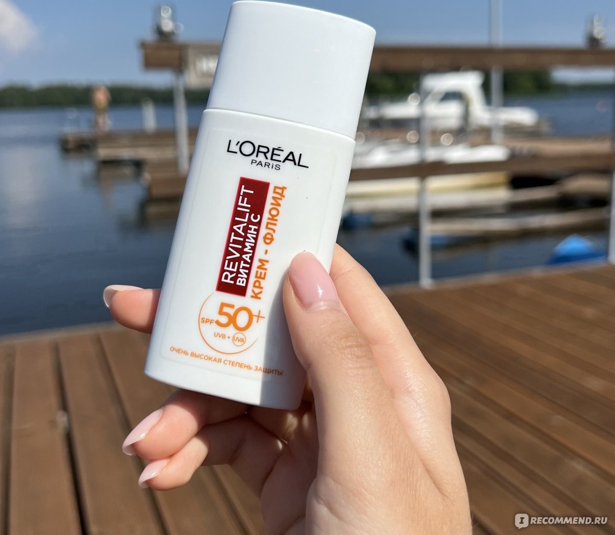 L'Oreal Revitalift Витамин С SPF 50+ — белый флакон солнцезащитного флюида в руке на набережной